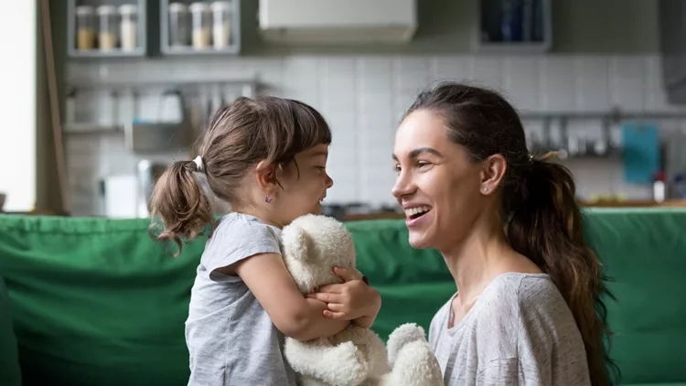 Smiling young mum talking with little daughter