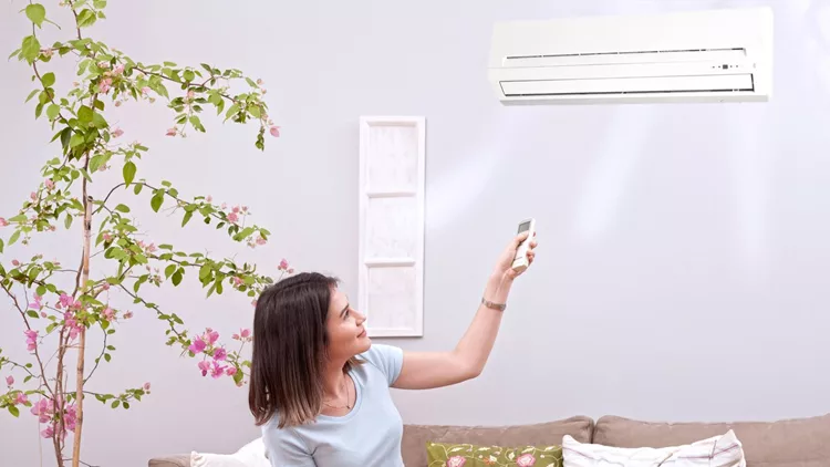 woman using remote control air conditioner