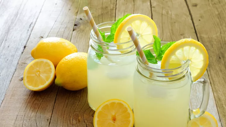 Mason jar glasses of homemade lemonade on rustic wood