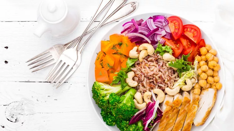 Buddha bowl dish with chicken fillet, brown rice, pepper, tomato, broccoli, onion, chickpea, fresh lettuce salad, cashew and walnuts. Healthy balanced eating. Top view. White background