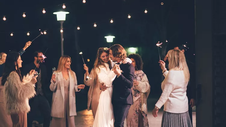 Happy wife and groom dancing at night outdoors wedding reception