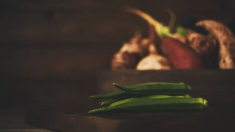 Still life of okra with crate of mixed vegetables