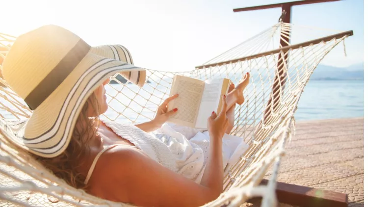 young-woman-reading-a-book-in-a-hammock-at-sunset-picture-id818507804