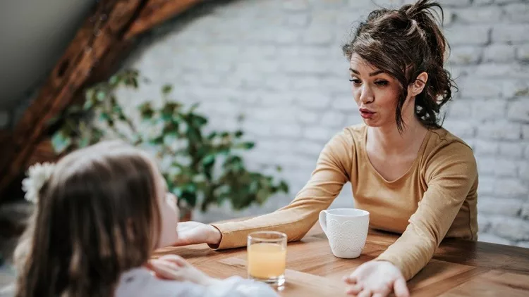 Young mother talking to her small daughter at home.