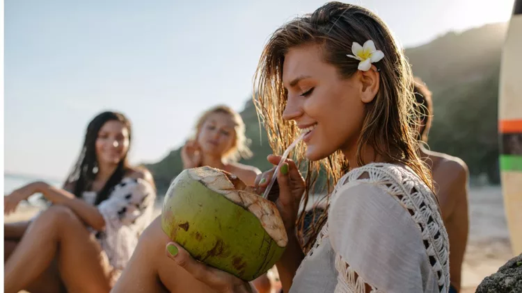 attractive-woman-drinking-coconut-water-with-friends-picture-id598246018