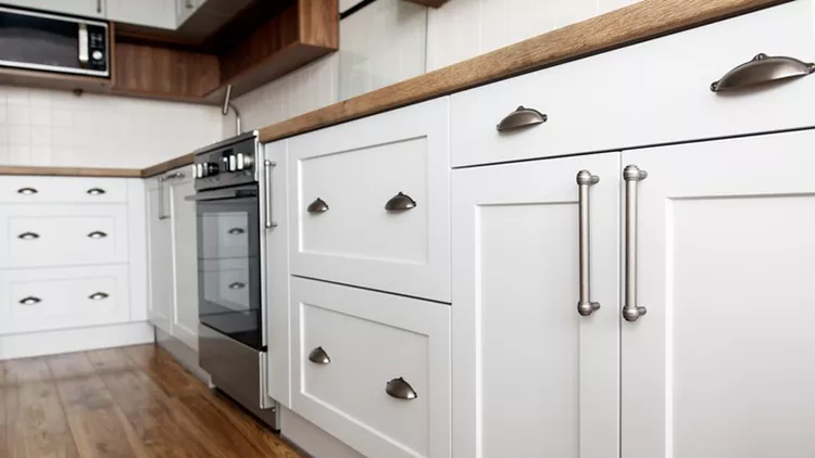 Stylish light gray handles on cabinets close-up, kitchen interior with modern furniture and stainless steel appliances. kitchen design in scandinavian style