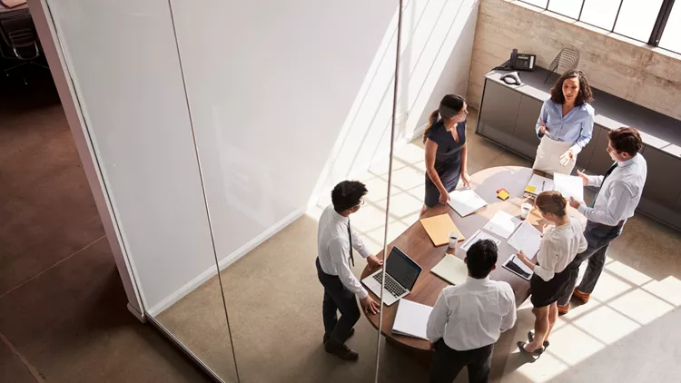 Female manager in team meeting, elevated view through window