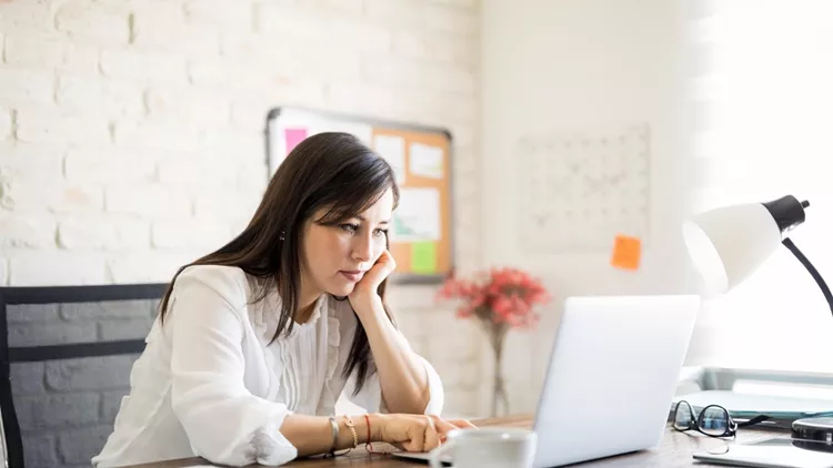 Bored woman working on laptop in office