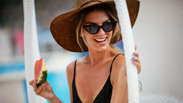 Woman enjoying slice of watermelon at swimming pool