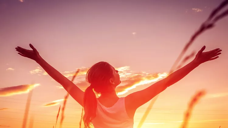 Free and happy woman raises arms against the sunset sky. Harmony and balance