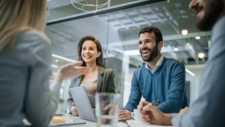 Happy businessman talking to his colleague on a meeting in the office.