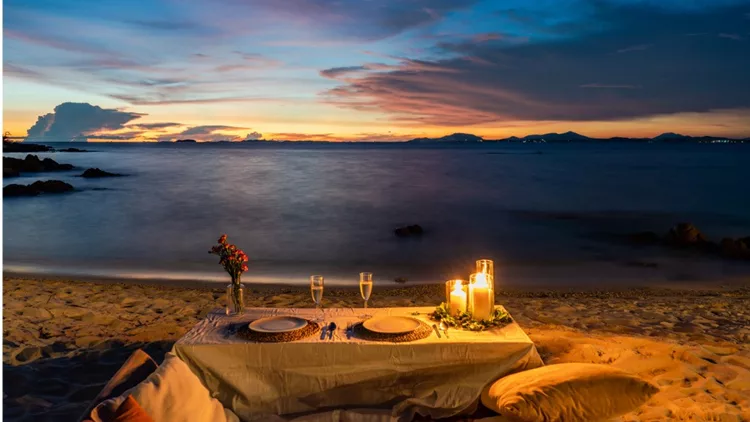 romantic-dinner-table-set-beside-the-beach-in-the-sunset-twilight-at-picture-id1161301468
