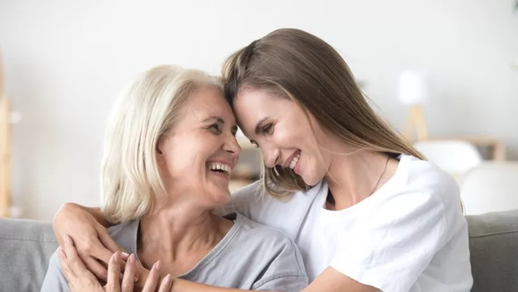 Happy loving older mother and grown millennial daughter laughing embracing