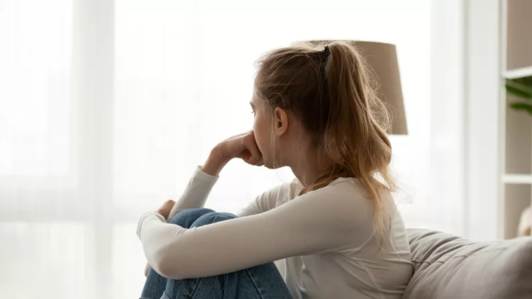 Upset woman sitting on couch alone at home