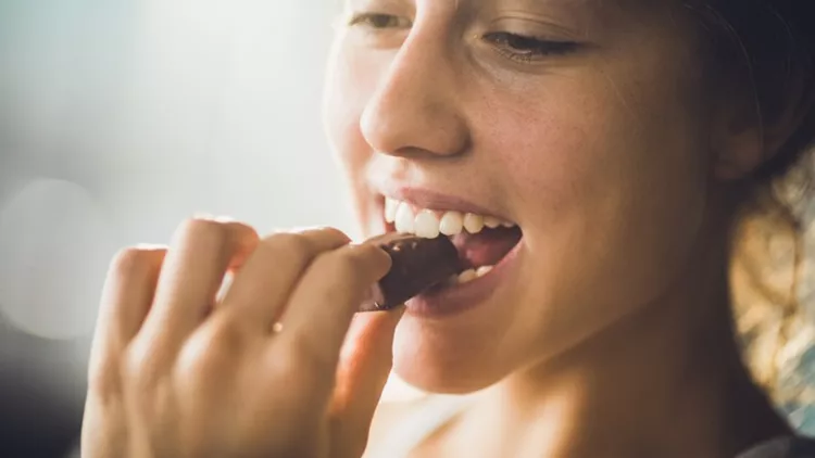 Close up of a happy woman eating chocolate.