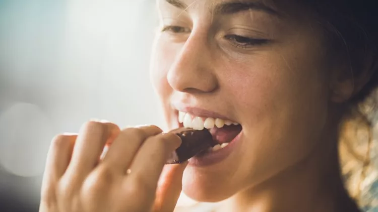 Close up of a happy woman eating chocolate.