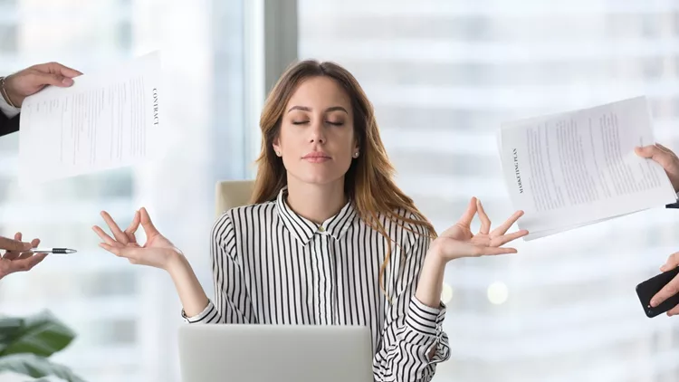 Calm female executive meditating taking break avoiding stressful job