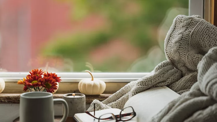 A cozy reading nook in the fall with a blanket and coffee