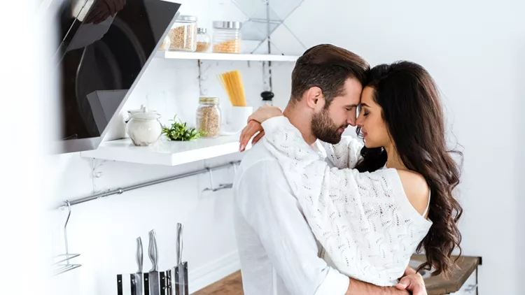 lovely gently couple embracing with closed eyes at kitchen