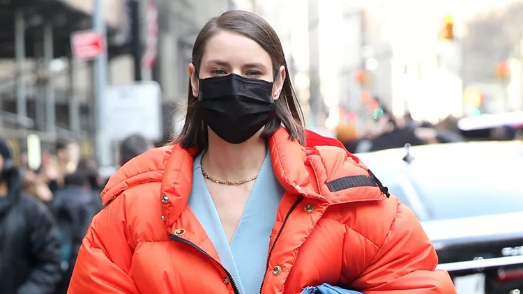 Influencer Marina Ingvarsson Is Seen In A Bright Orange Puffer Coat And Face Mask Outside Michael Kors During New York Fashion Week At American Stock Exchange In New York City