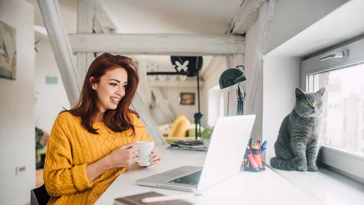 Happy young redhead working on a laptop