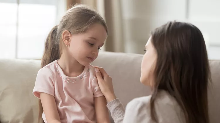 Loving mom talking to upset little child girl giving support