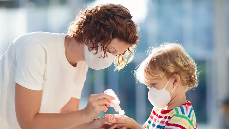 Mother and child with face mask and hand sanitizer