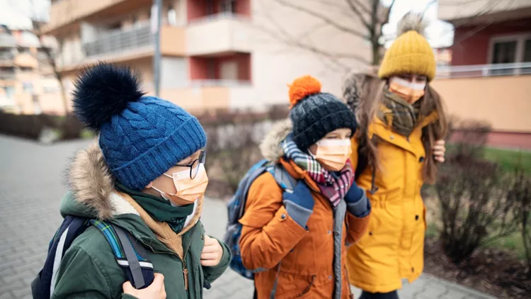Three kids wearing anti virus masks going to school