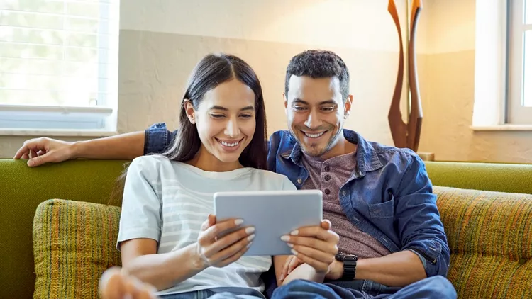 Smiling young couple using digital tablet at home