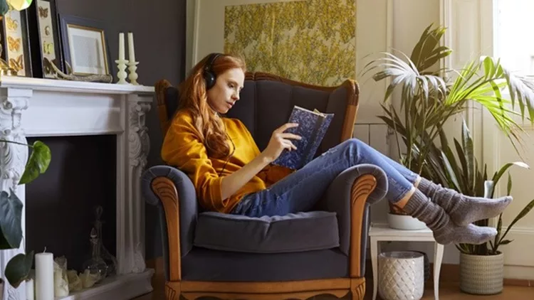 Woman reading book while listening to music