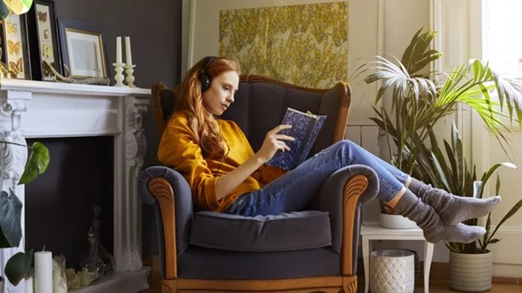 Woman reading book while listening to music