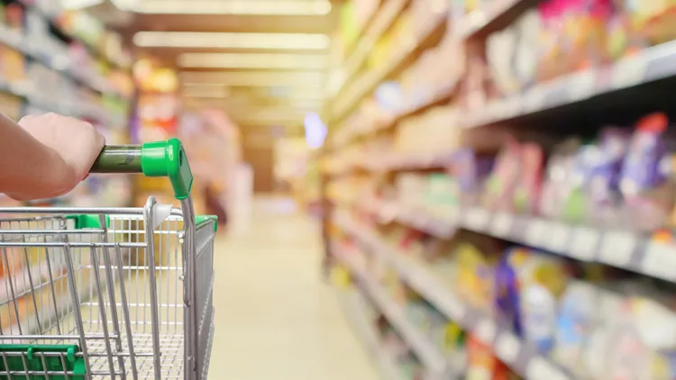 shopping cart in supermarket aisle with product shelves interior defocused blur background