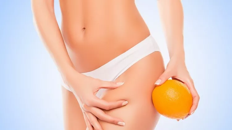 Woman in panties holding orange near hip and checking fat