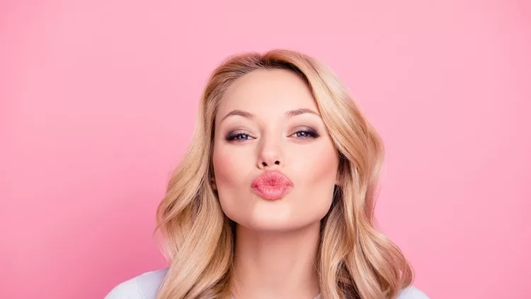 Portrait of cute lovely girl in casual outfit with modern hairdo sending blowing kiss with pout lips looking at camera  isolated on pink background. Affection feelings concept