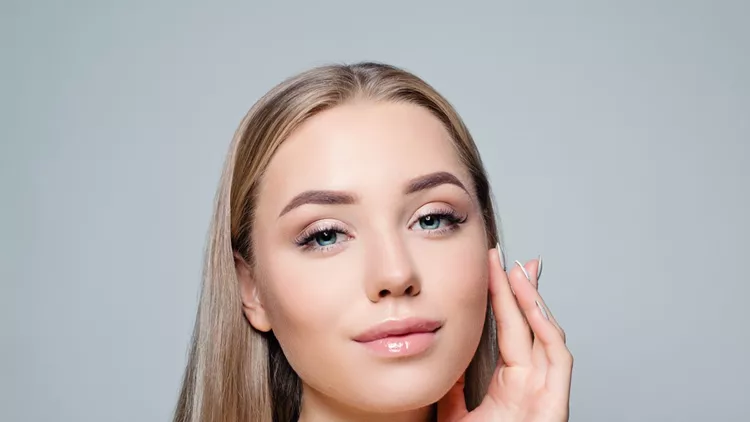 Beautiful blonde woman with long healthy curly hair and clear skin. Facial treatment, haircare and cosmetology