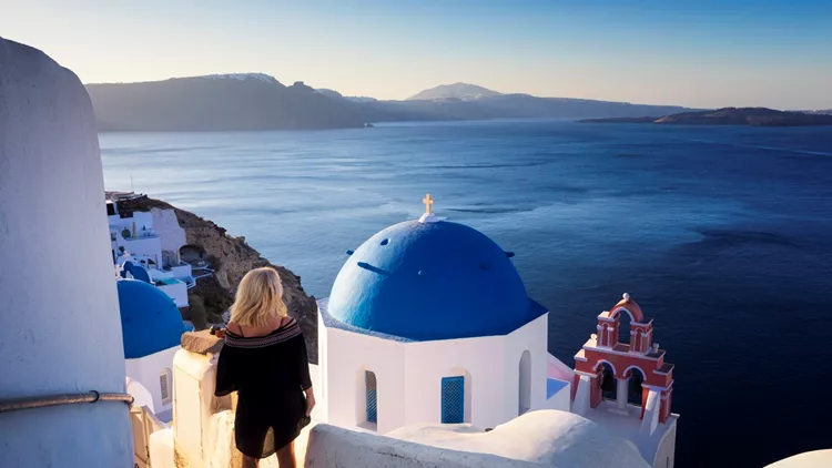 Young woman looks at the marine landscape, Santorini, Oia, Greece