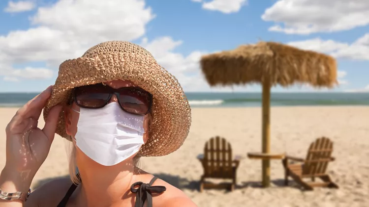 Vacationing Woman Wearing Face Mask on Sandy Beach.