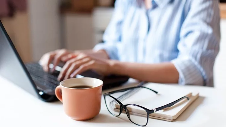 Remote working from home. Freelancer workplace in kitchen with laptop, cup of coffee