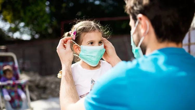 Single father applying pollution mask to his daughter