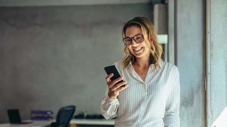 Smiling businesswoman using phone in office