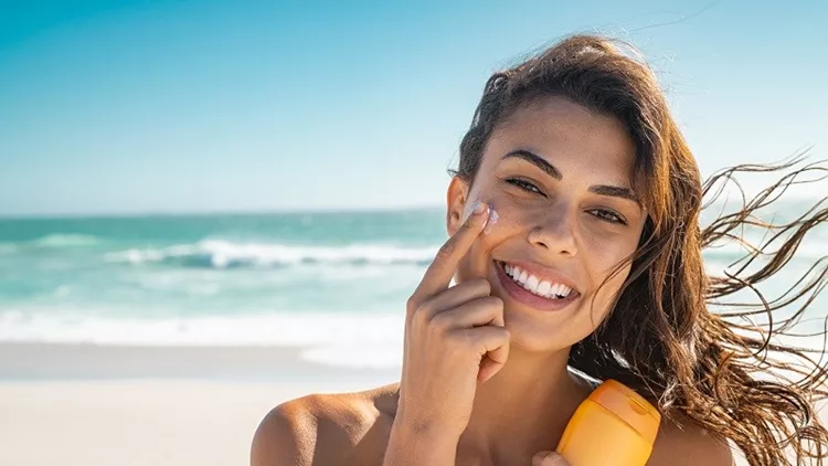 Smiling woman applying sunscreen