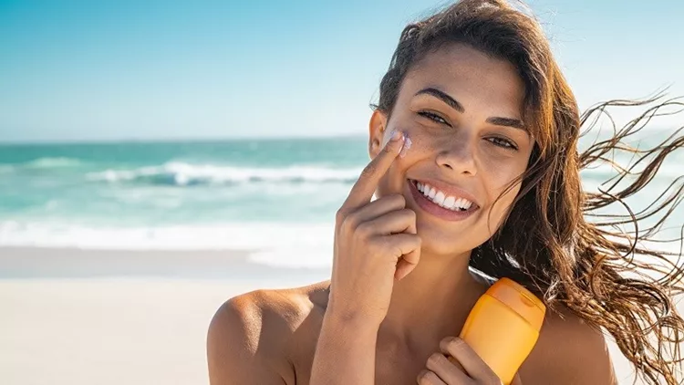 Smiling woman applying sunscreen