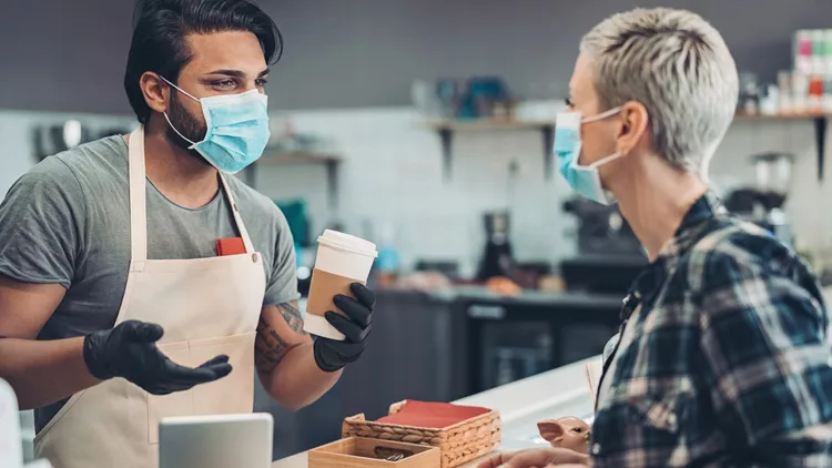 Coffee shop owner working with a face mask and protective gloves