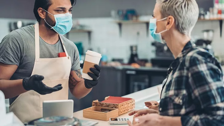 Coffee shop owner working with a face mask and protective gloves