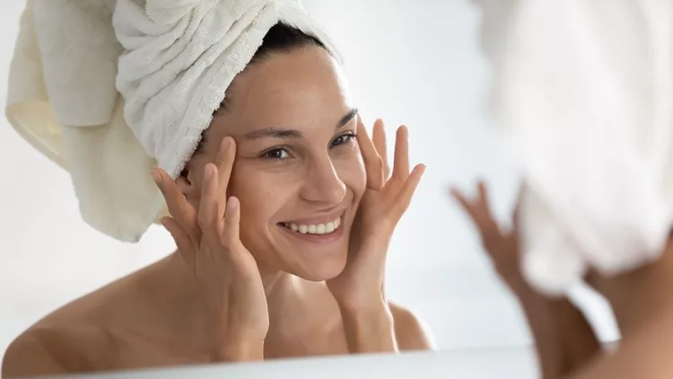 After beauty home procedure woman looking at skin feels satisfied