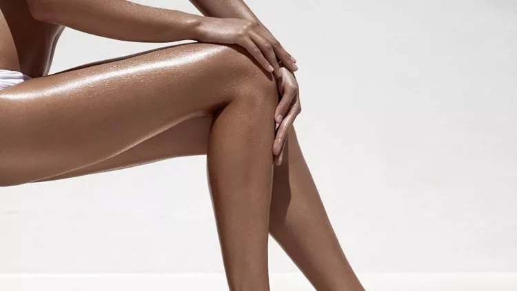 Beautiful woman tan legs. Against white wall.