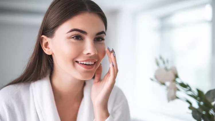 Satisfied girl doing face treatment in morning