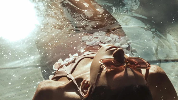 Stunning beautiful dark hair girl in swimsuit in the pool with summer vibes on a vacation in water