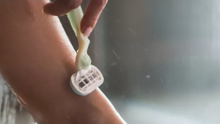 close-up-of-unrecognizable-woman-shaving-her-leg-under-the-shower-picture-id1034830988