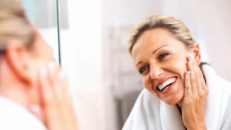 Happy mature woman admiring herself in the mirror